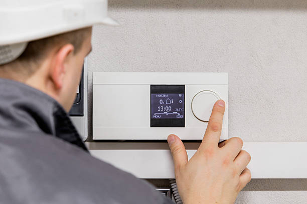 Engineer adjusting thermostat for efficient automated heating system.