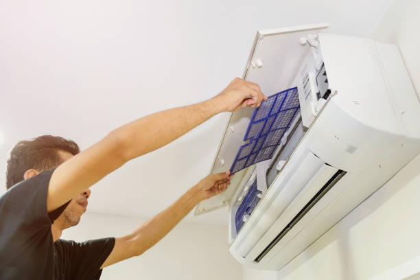 A man is removing the air filter of the air conditioner for cleaning.