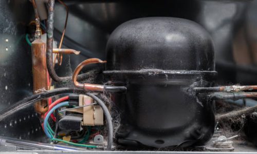 Refrigerator backside including corroded copper pipes, electrical wiring and dust and pet hair. Concept for maintaining and repair appliances. Selective focus.