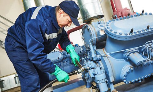 service engineer worker at industrial compressor refrigeration station repairing and adjusting equipment at manufacturing factory